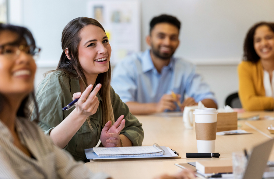 Junge Kandidat:innen für das Sales Traineeprogramm sitzen am Tisch und diskutieren.