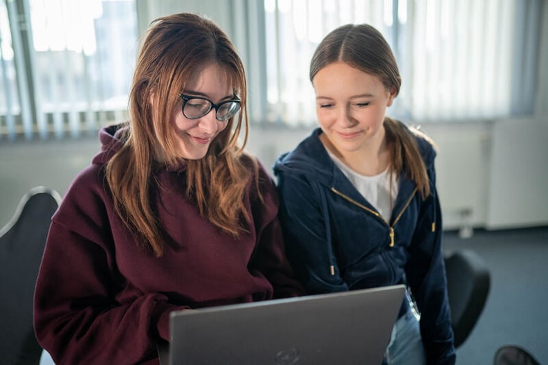 Azubi erklärt Praktikanten etwas am Laptop