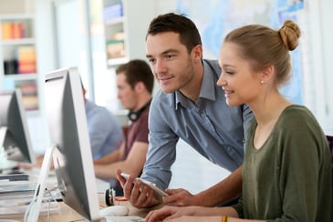 Auszubildende vor ihrem PC mit ihrem Mentor.