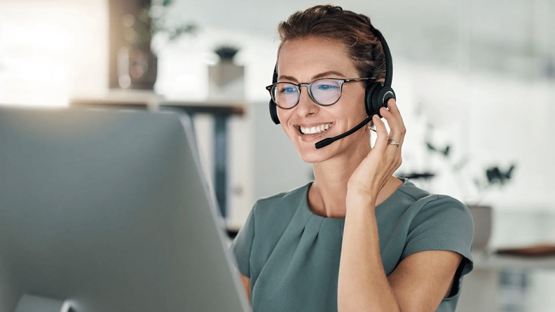 esm-woman-smiling-sitting-headset-costumer-service-work-environment