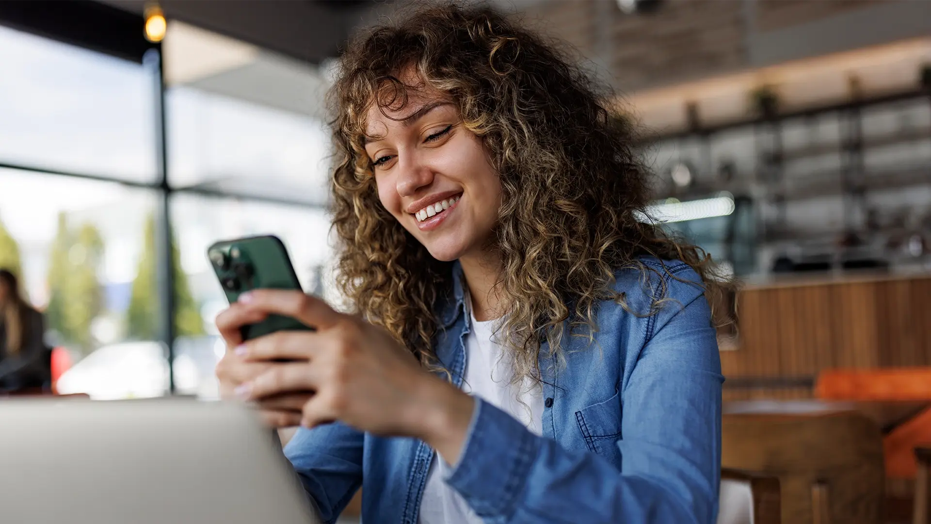woman sitting at home using smartphone and laptop