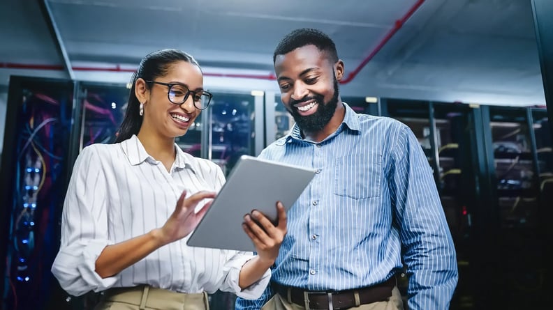 cyber-security-woman-and-man-smiling-at-tablet-in-server-room