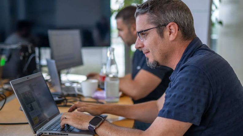 serviceware-man-werkt-op-laptop-glimlachend