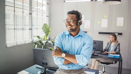 esm-customer-service-man-smiling-headset-arms-crossed-in-office