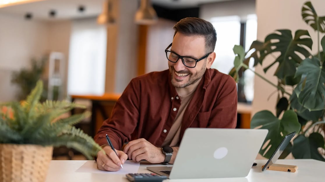 esm-customer-service-man-writing-smiling-with-laptop