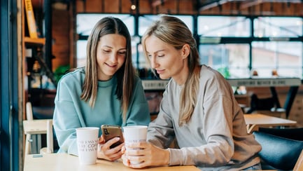 esm-customer-service-two-women-in-cafe-looking-at-phone