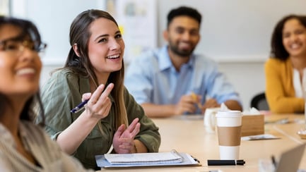 Jonge stagiairs zitten aan hun bureau en discussiëren.