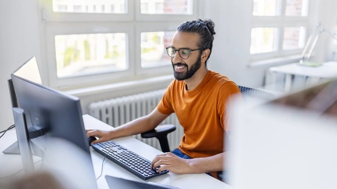 Junger Mann sitzt im Büro vor seinem PC.