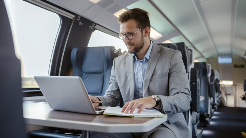 financial-man-with-laptop-in-train