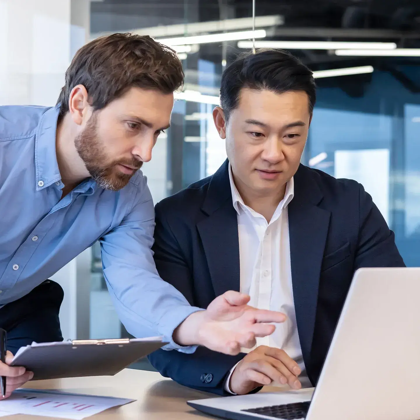 Zwei Männer überprüfen ihre Arbeit auf einem Laptop-Bildschirm