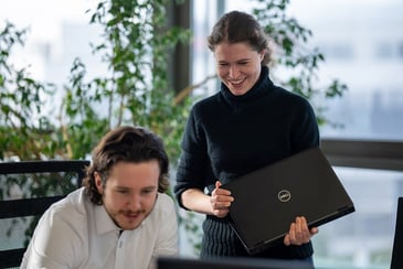 Zwei Kolleg:innen sind im Büro und schauen auf einen Bildschirm, dabei klären sie etwas.