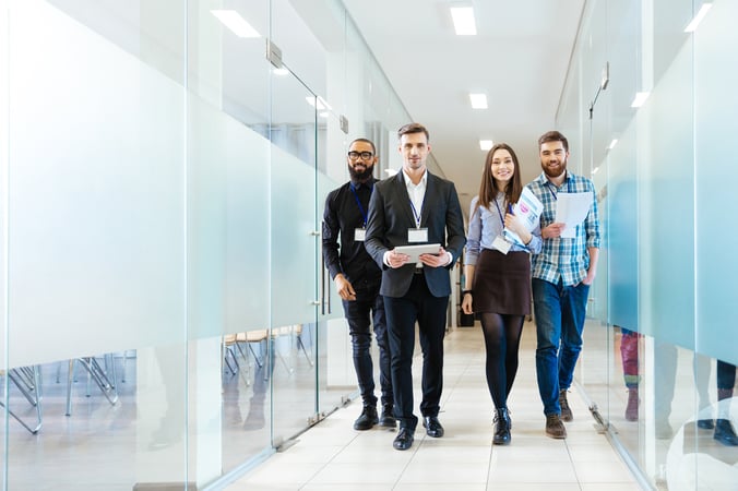 Eine Gruppe junger Geschäftspersonen geht gemeinsam den Büro Flur entlang