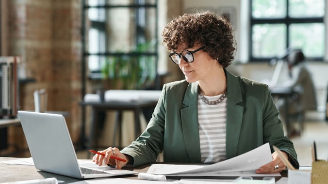 Eine Frau arbeitet konzentriert am Laptop im Büro und plant etwas
