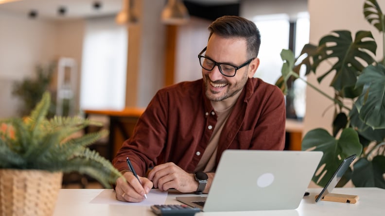 Mann sitzt zufrieden im Home-Office umgeben von grünen Pflanzen