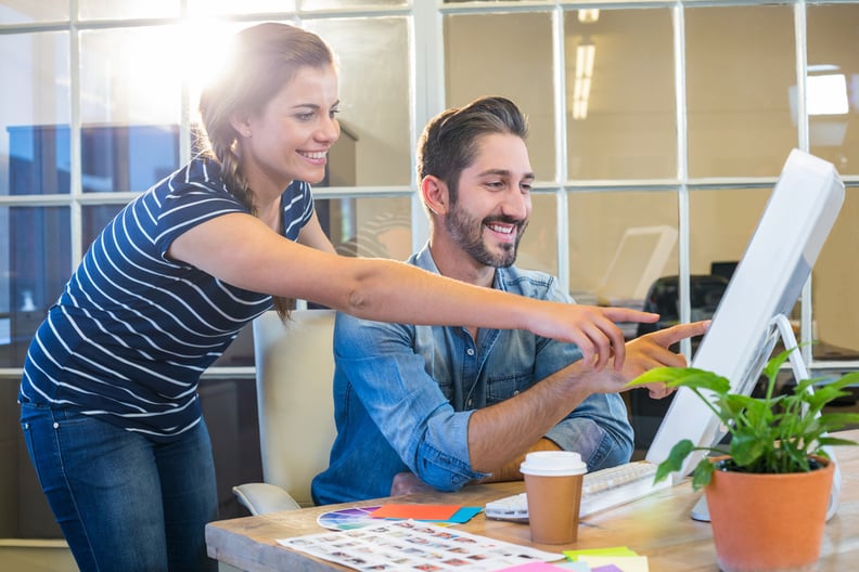 Kolleginnen und Kollegen arbeiten fröhlich im Büro am Computer