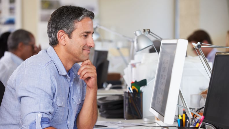 Geschäftsmann sitzt am Schreibtisch und schaut aufmerksam auf den Bildschirm