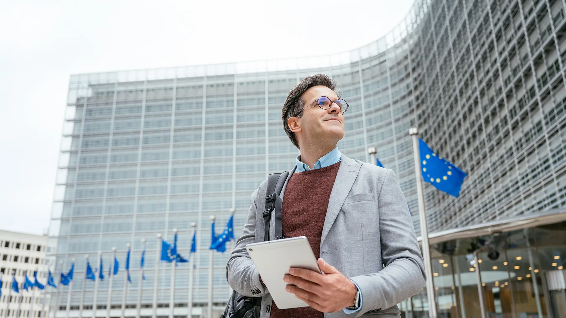 Man smiling holding tablet near government building
