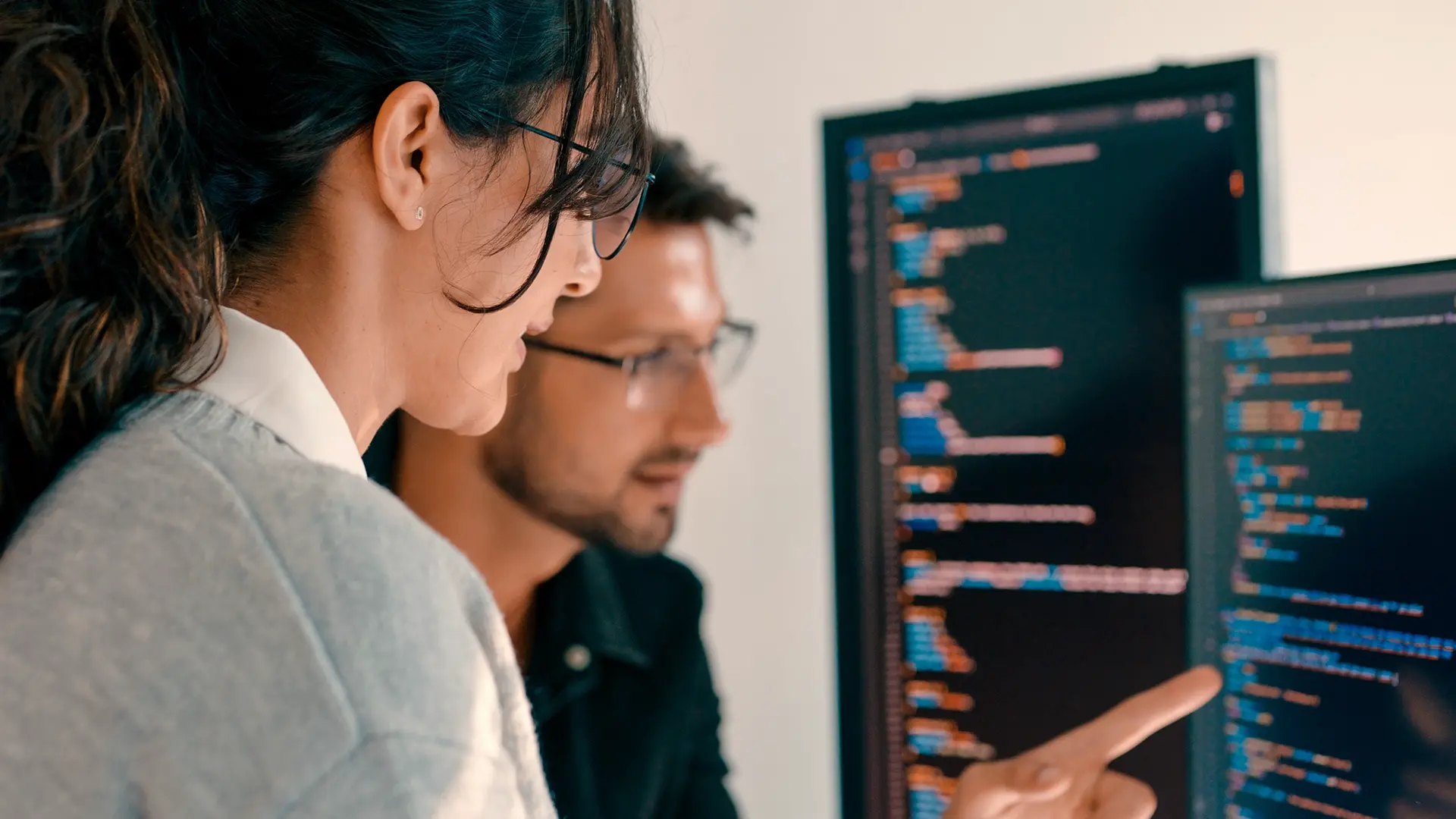 Colleagues reviewing code on the screen, woman indicating a point