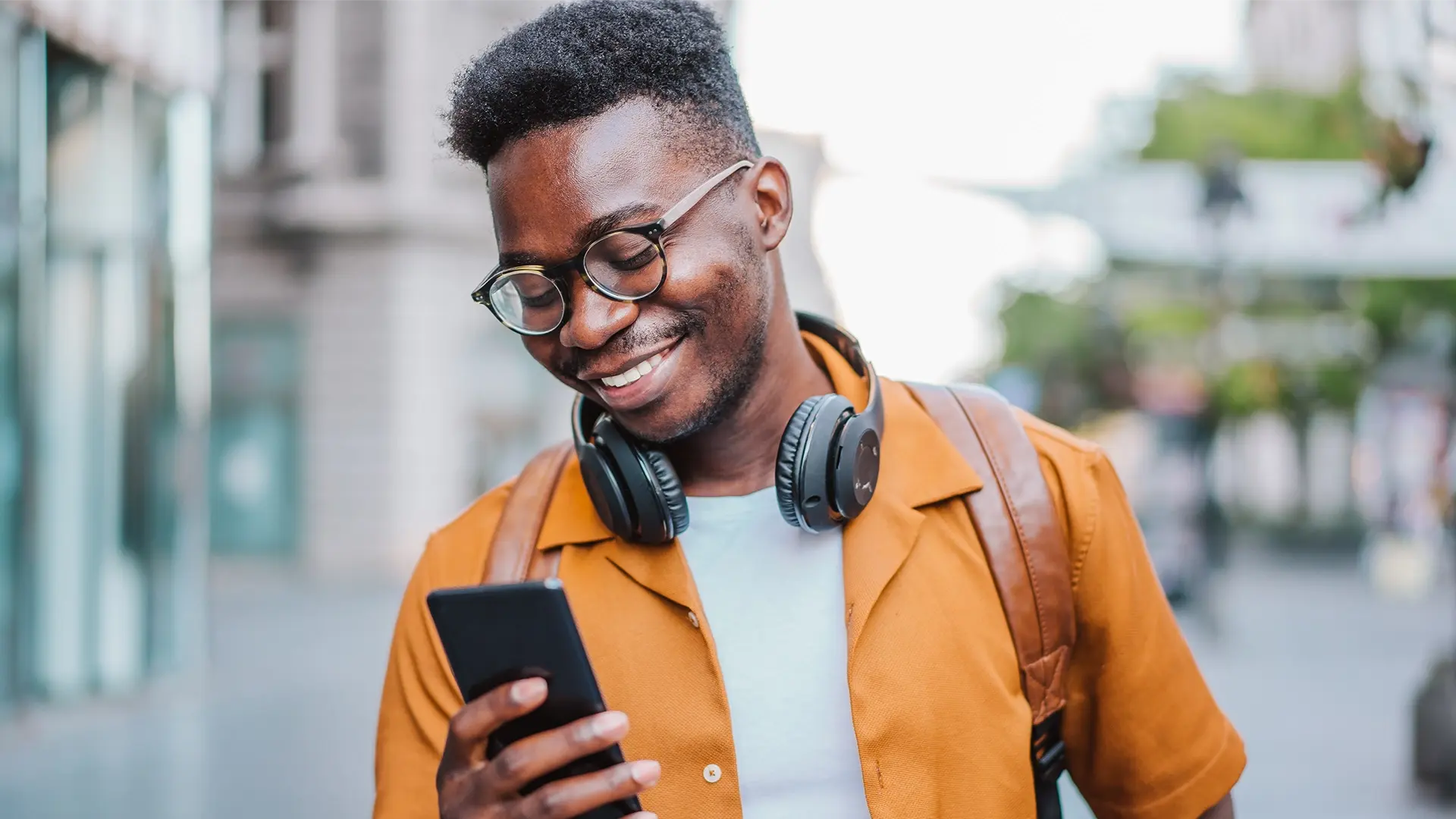 man smiling standing smartphone public street