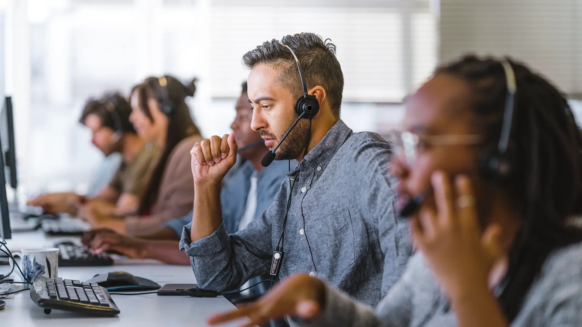 people working at desks with headsets in call center environment