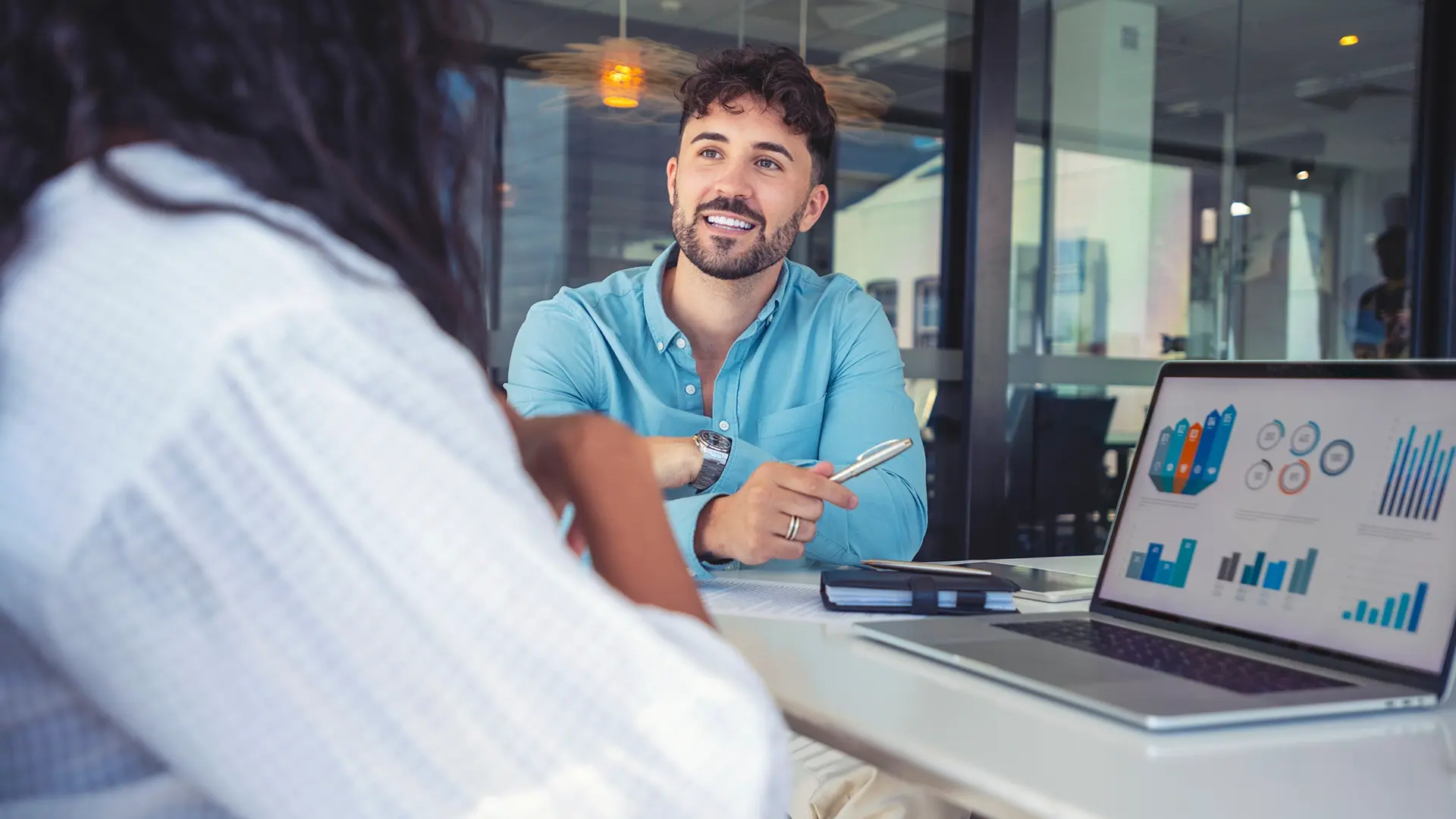 Two colleagues in conversation, looking at graphs and smiling