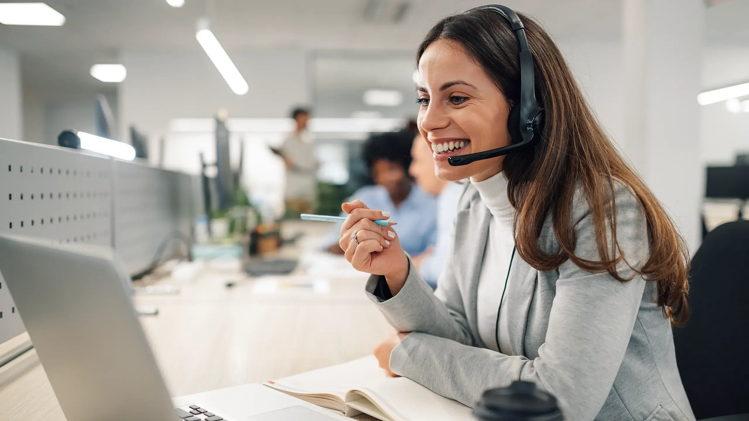 Mitarbeiterin im Kundenservice mit Headset nutzt Laptop für Wissensmanagement und KI-gestützte Supportanfragen